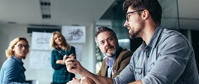 two males and two females having a meeting in a boardoom.